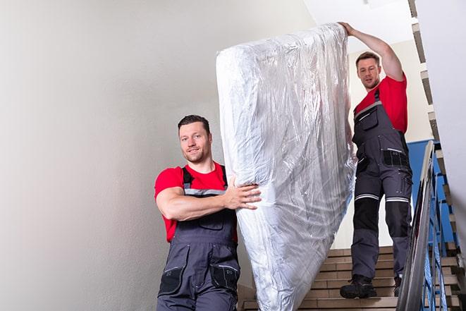 workers maneuvering a box spring through a narrow hallway in Berkeley